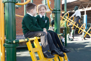 Two students at St Peter Chanel Catholic Primary School Regents Park sitting and talking on play equipment